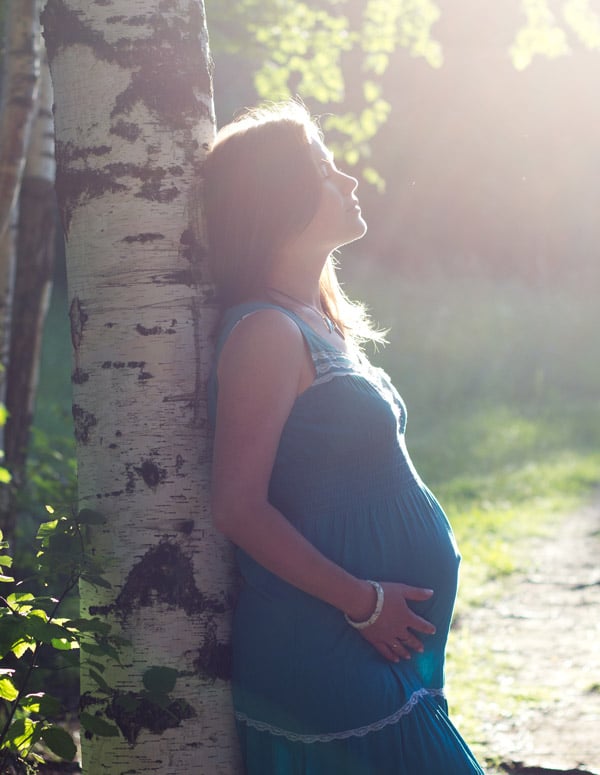 femme enceinte adossée à un arbre